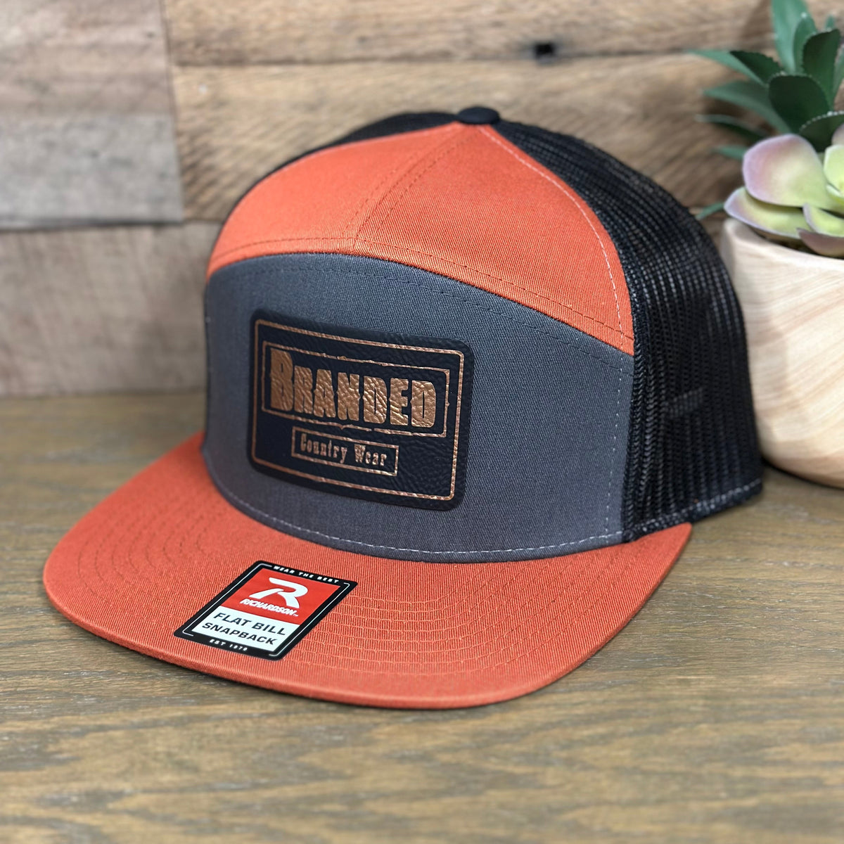 Branded Country Wear Leather Logo Patch 7 Panel Trucker Hat in Charcoal, Burnt Orange, & Black